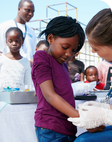 Child receiving medical checkup outdoors.