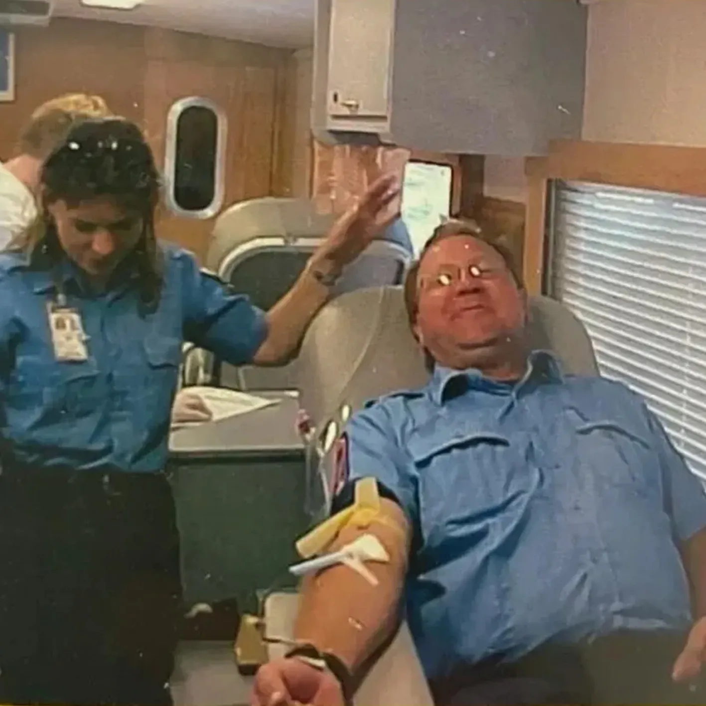 Blood drive volunteer assisting donor.