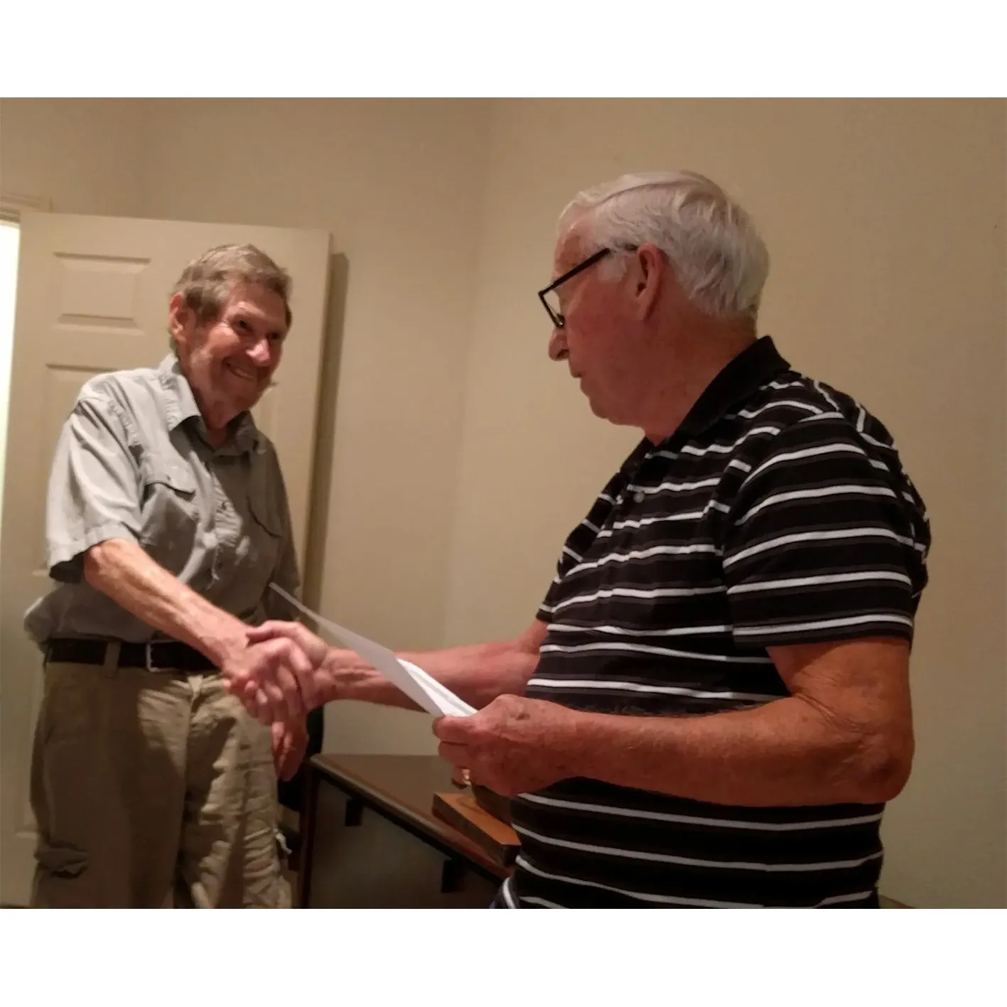 Two men shaking hands, award ceremony.