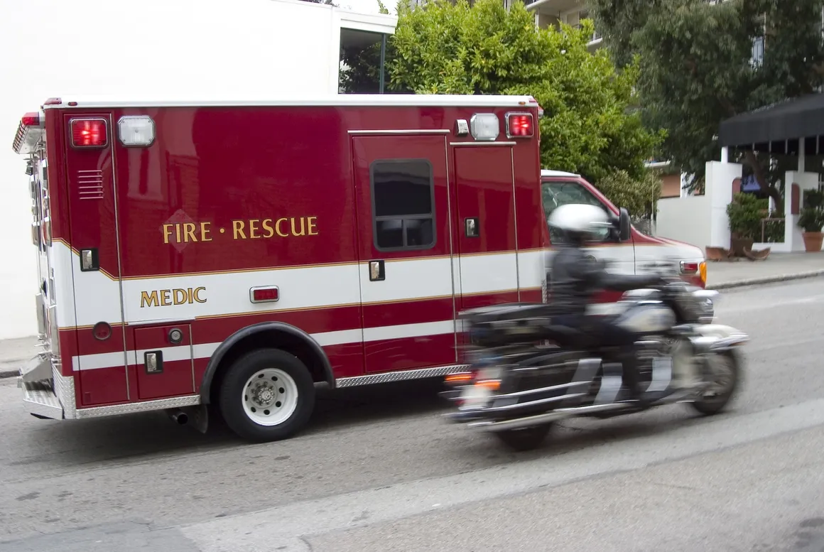 Here's an alt tag for the image: Ambulance and motorcycle in motion.