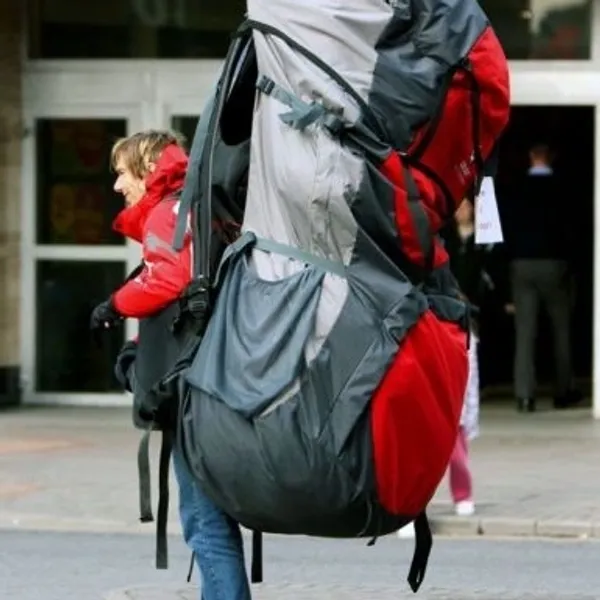 Person carrying enormous backpack outdoors.