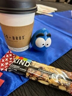 Coffee cup, snack bar, blue toy on table.
